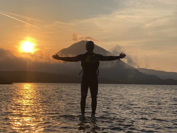 A man seeminly stands on the water while kayaking on Dunlewey Lake