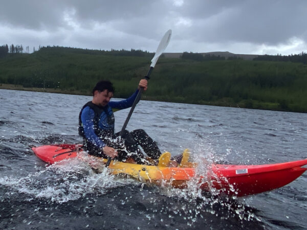 Kayaking on Dunlewey Lake with a man pushing through water with water spray