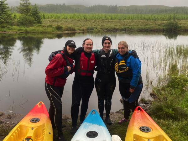 Kayaking on Dunlewey Lake with a group of friends posing in front of their canoes