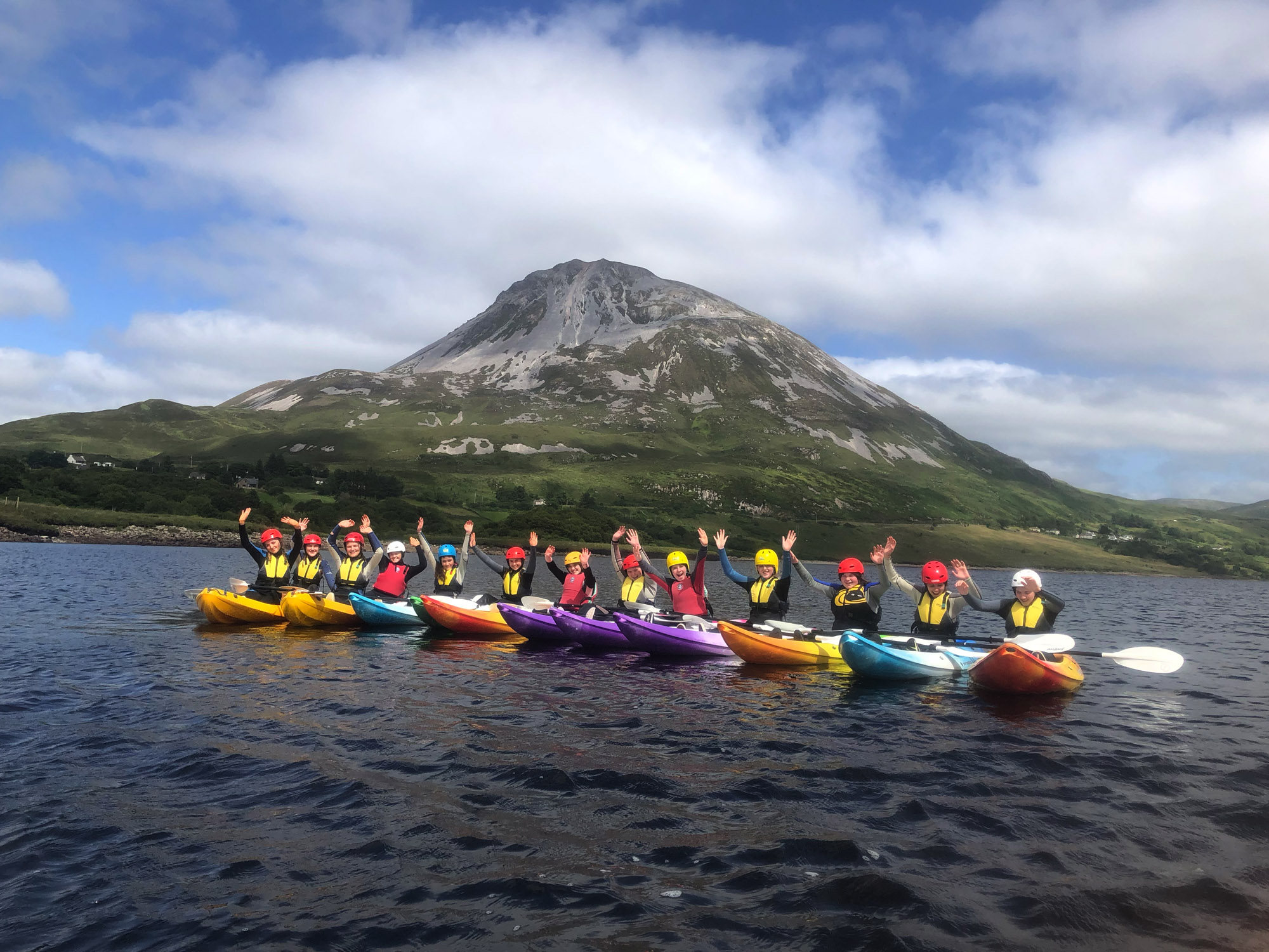 A school trip kayaking on Dunlewey Lake with kids in their kayaks in a line on the lake